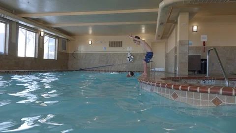Young boy flips into a swimming pool Stock Footage 106630665