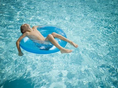 Young boy floating on life ring in swimming pool Stock Photos
