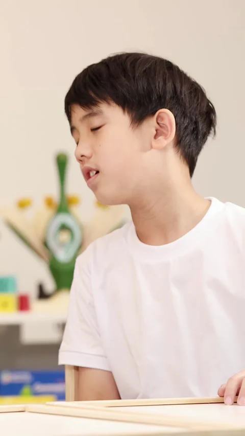 Young Boy Focused on Learning Activity in a Bright Classroom Setting Stock Footage 326386662