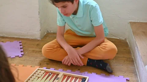 Young boy focused on playing backgammon with a friend indoors Stock Footage 290052390