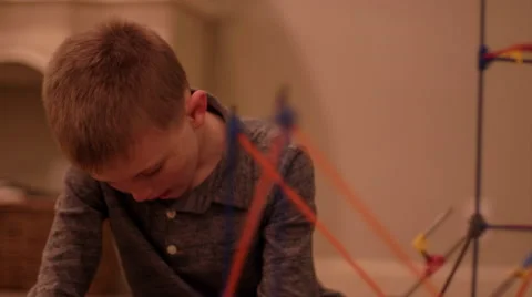 A young boy focusing on building a plastic toy structure at home Stock Footage 63220525