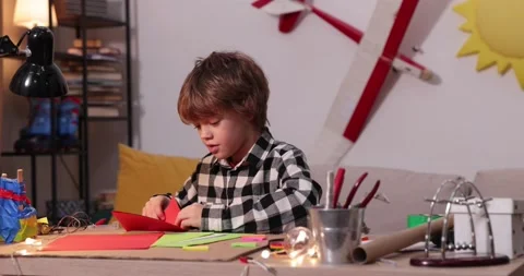 Young boy folding a paper airplane and ships, causasian boy playing with paper Stock-Footage 171869679