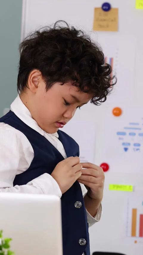 Young Boy in Formal Vest Adjusting Clothes in Modern Classroom Stock Footage 338155658