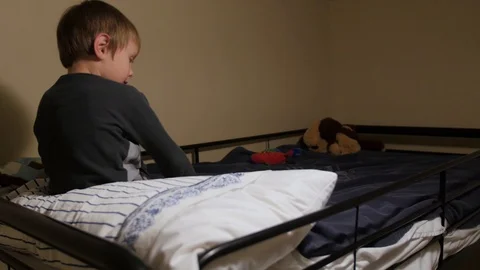 Young boy gets in his bed covers on the top bunk ready for bed Stock Footage 86712285