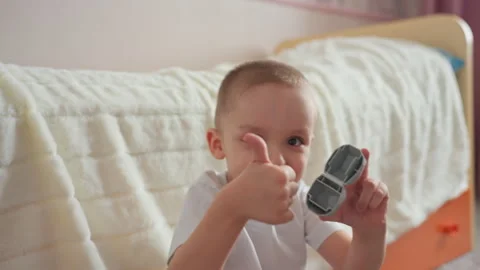 Young boy giving thumbs up while holding small toy, satisfied smile and playful Stock Footage 331948296