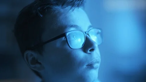 Young boy with glasses in blue light looking away Stock Footage 128500966