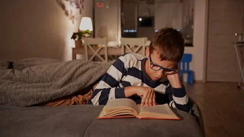Young boy in glasses deeply immersed in reading book. Stock Footage 296199744