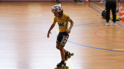 A young boy glides on one foot during an indoor inline skating event Stock Footage 312453770