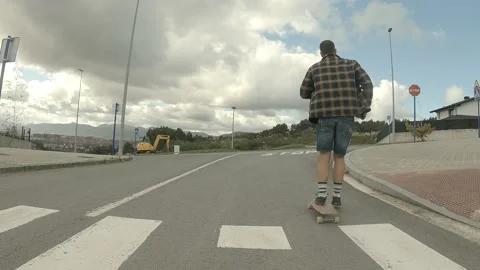 Young boy gliding with a longboard down the road Stock Footage 141085197