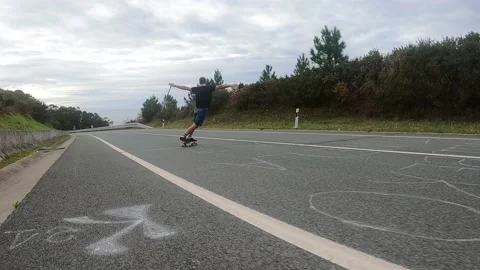 Young boy gliding with a longboard down the road Stock Footage 141085330