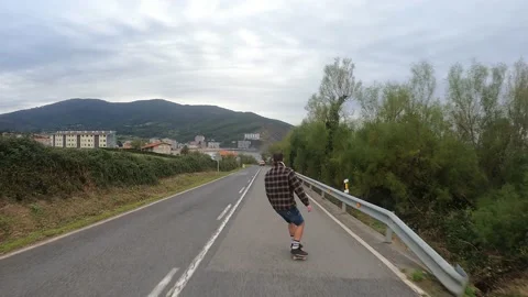 Young boy gliding with a longboard down the road Stock Footage 141085639