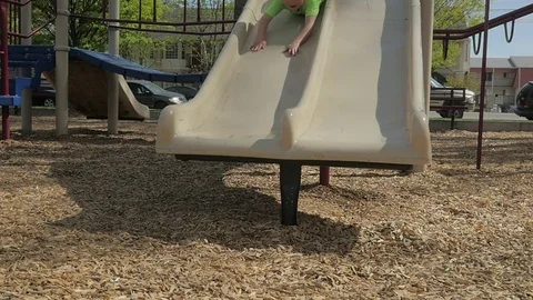Young boy goes face first down a slide at the park. Video stock 75862844