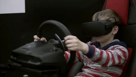 Young boy with Goggles and Playing Video Games of Racing Car with ride simulator Stock Footage 84332180