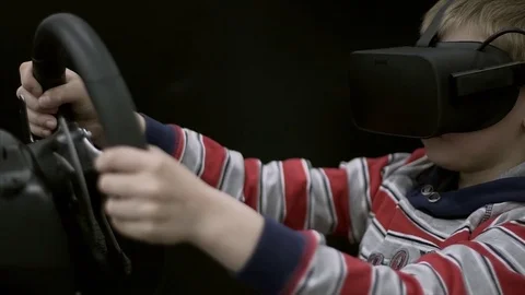 Young boy with Goggles and Playing Video Games of Racing Car with ride simulator Stock Footage 84332229