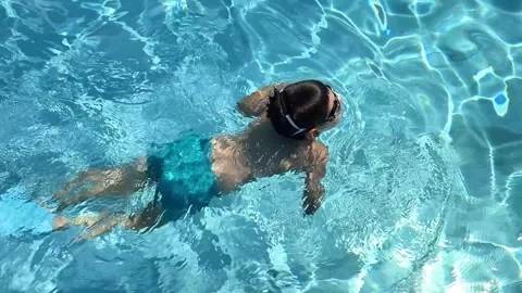 Young boy in goggles swimming in clear blue pool water Stock Footage 341400863