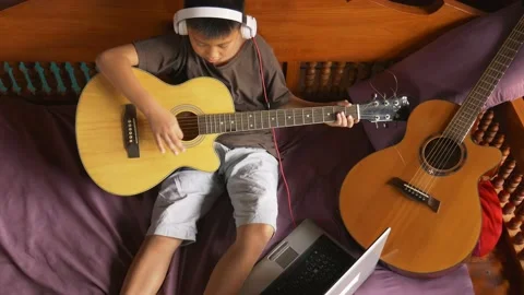 Young boy with a guitar plays the classical guitar 動画素材 141738456