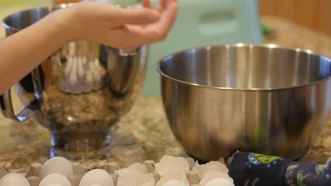 Young boy hands mom an egg and she separates it into metal bowl Stock Footage 86712489