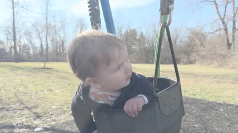 Young boy hanging in child swing at playground 4k Stock Footage 332955564