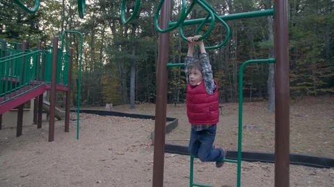 Young boy hangs from monkey bars Stock Footage 81538031