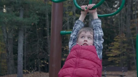 Young boy hangs from monkey bars and falls - close up Stock Footage 81556173