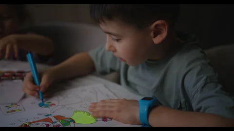 A young boy is happily sitting at a table using markers to draw pictures Stock Footage 275823711