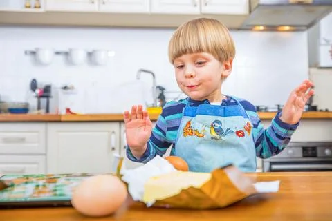 Young Boy Having Fun Baking with Eggs in a Bright Modern Kitchen Stock Photos