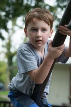 Young boy having fun outside at park on a playground climbing set Stock Photos
