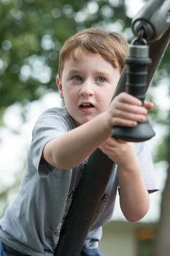 Young boy having fun outside at park on a playground climbing set Stock Photos
