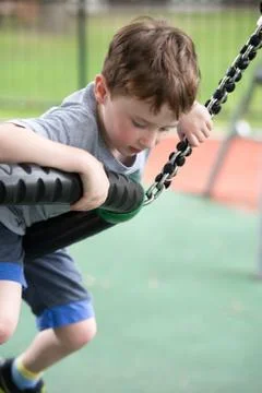 Young boy having fun outside at park on a playground climbing set Stock Photos
