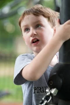 Young boy having fun outside at park on a playground climbing set Stock Photos