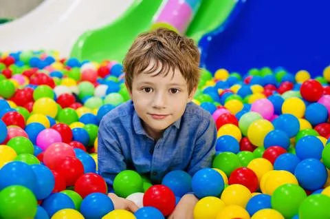 Young boy having fun playing with colorful plastic balls Stock Photos