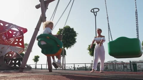 Young boy having fun on the swing. His mother or babysitter his swinging him and Stock Footage 255072570