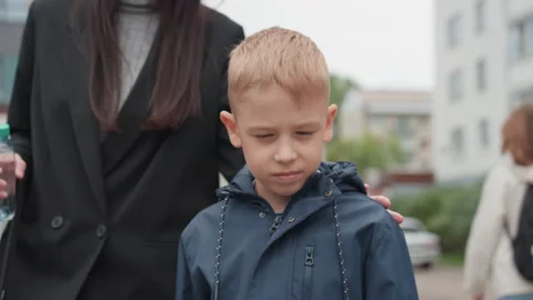 Young boy heads to class. Boy and mother walk to school entrance. Urban setting Stock Footage 338282041