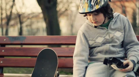 Young boy in helmet putting on protective pads, outdoors, steadicam shot Stock Footage 2249202