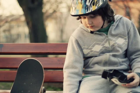 Young boy in helmet putting on protective pads, outdoors, steadicam shot Stock-Footage 2249372