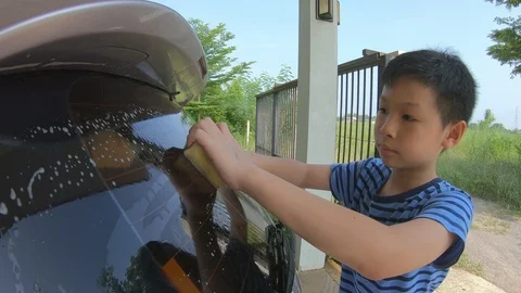 Young boy helping his parent wash car Stock Footage 97914468