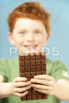 Young Boy Holding Bar Of Chocolate Stock Photos