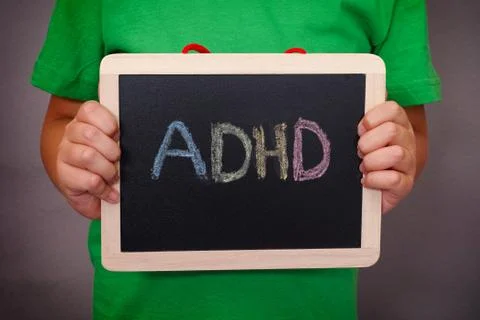 Young boy holds ADHD text written on blackboard Stock Photos
