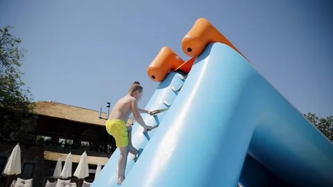 A young boy holds onto the bars of a water slide and climbs to the top Stock Footage 267615043
