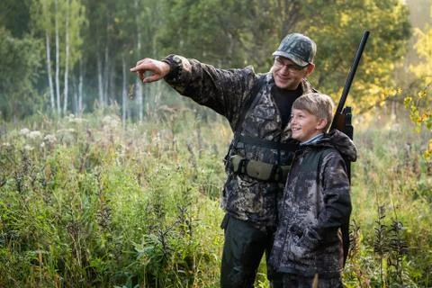 A young boy on the hunt with an experienced instructor in the forest. Autumn Stock Photos