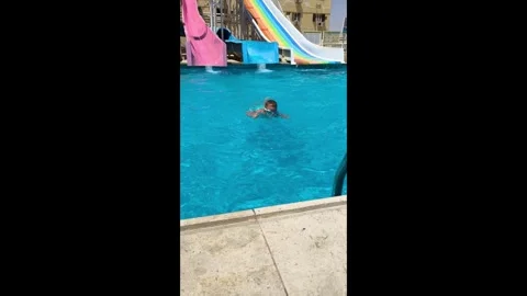 Young boy joyfully slides down a water slide. young boy blue swimming trunks sli Stock Footage 334232112