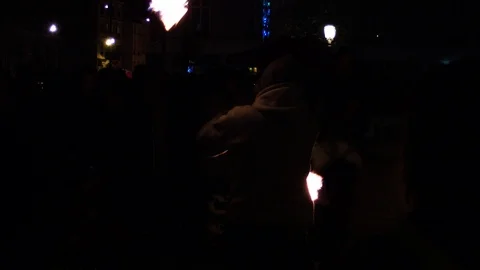 A young boy is juggling with two ignited objects amoung a crowd during the Stock Footage 99990653