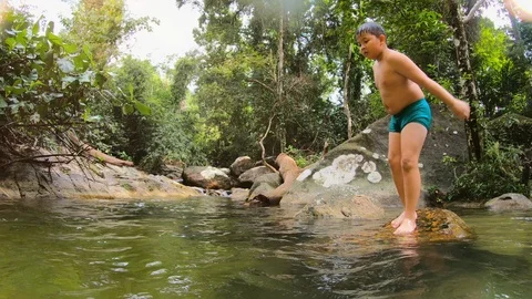 Young boy jumping happily into the river and water splashes Stock Footage 125920293