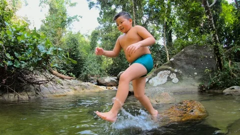 Young boy jumping happily into the river and water splashes Video stock 125920750