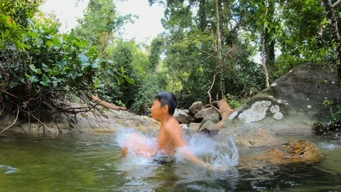 Young boy jumping happily into the river and water splashes Stock Footage 125920786