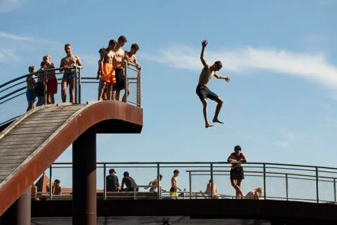 Young boy jumping from a high point with arms and legs out into the water whi Stock Photos