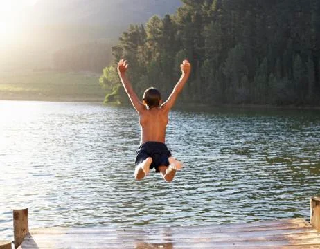 Young boy jumping into lake Stock Photos