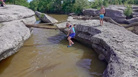 Young boy jumping into river while his brother looks on slow motion Stock-Footage 142394648