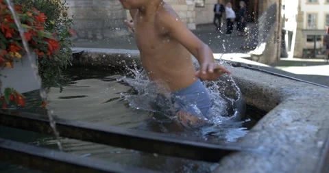 Young boy jumping into water in a public fountain, slow motion at 800 fps, .. Stock Footage 288126275