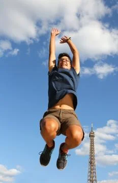 Young boy jumps with Eiffel Tower on background in Paris France Fotos de archivo